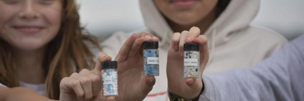 Students holding containers of different types of plastic